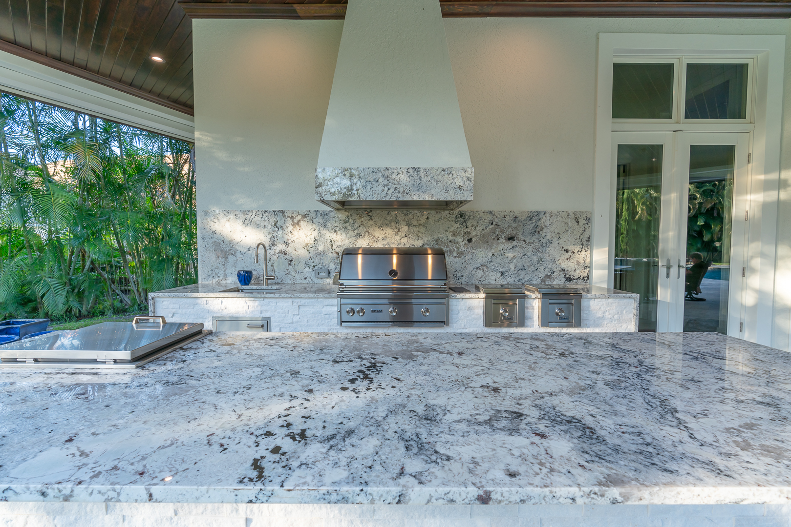 Premium outdoor kitchen with white granite countertops and hood — Jupiter, FL