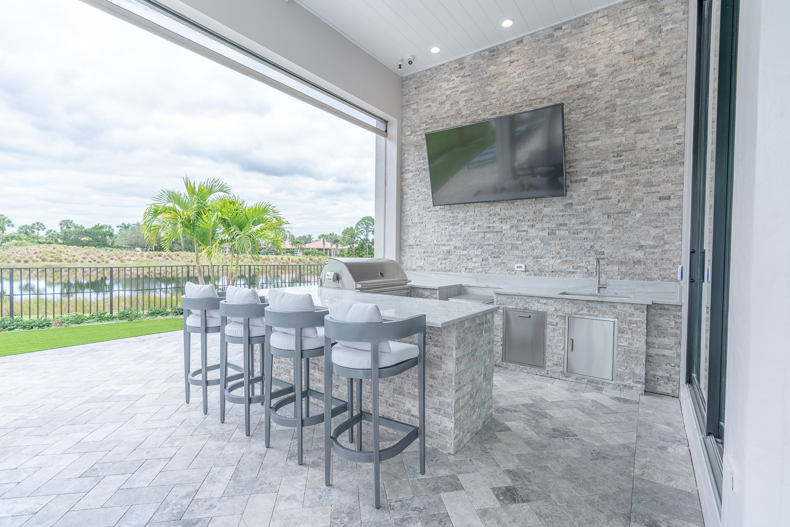 Custom outdoor kitchen with stone bar and lake view — Palm Beach Gardens, FL